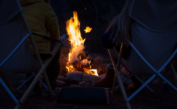 A Firewood Carrier beside a stone circle campfire.